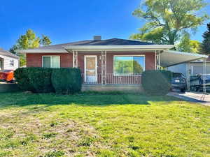 View of front of property with a porch, a carport, and a front yard
