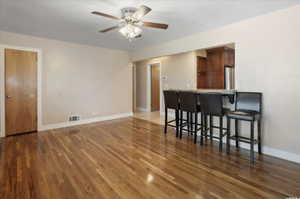 Living room with a ceiling fan, wood finished floors, and baseboards