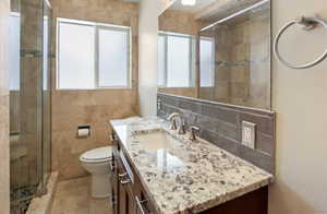 Bathroom featuring plenty of natural light, vanity, toilet, and a stall shower