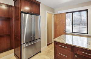Kitchen featuring freestanding refrigerator, light stone counters, baseboards, and light tile patterned flooring