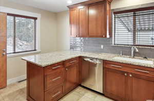 Kitchen featuring dishwasher, a sink, healthy amount of natural light, decorative backsplash, and recessed lighting