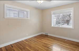 Spare room featuring a ceiling fan, wood finished floors, and baseboards