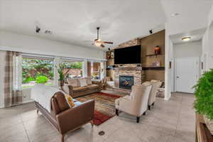 Living area with plenty of natural light, light tile patterned floors, ceiling fan, a fireplace, and lofted ceiling