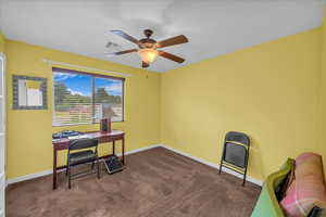 Carpeted home office featuring ceiling fan and baseboards