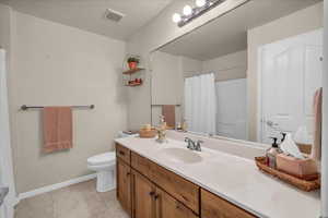 Full bathroom with baseboards, vanity, toilet, tile patterned floors, and a shower with curtain