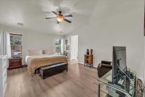 Bedroom featuring multiple windows, light wood-type flooring, baseboards, and lofted ceiling