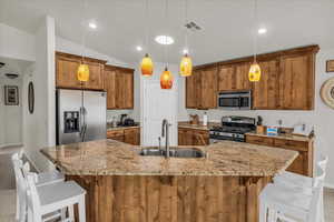 Kitchen featuring stainless steel appliances, a sink, brown cabinetry, a kitchen breakfast bar, and lofted ceiling