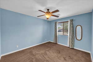 Carpeted spare room with ceiling fan and baseboards