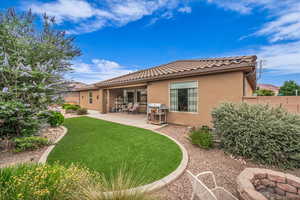 Rear view of property with stucco siding, a tile roof, and a patio