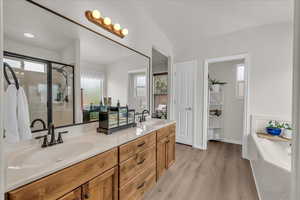 Full bath with double vanity, wood finished floors, a garden tub, and a stall shower