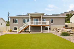 Back of property with stairway and covered deck, terraced landscaping, and open Flagstone patio