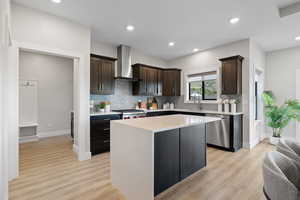 Kitchen with Bosch dishwasher, stainless steel appliances and range hood, dark wood cabinetry, and a center island with waterfall style quartz countertop.
