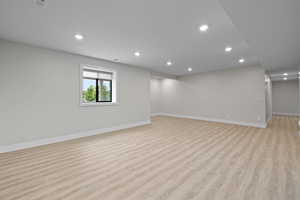 Basement living room featuring LVP flooring, recessed lighting, and daylight windows