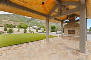 View of  covered patio featuring an outdoor stone fireplace, outdoor lighting, and a mountain view