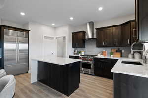 Kitchen featuring dark wood cabinetry, light quartz countertops, stylish tile backsplash, LVP flooring, and luxury stainless steel appliances.