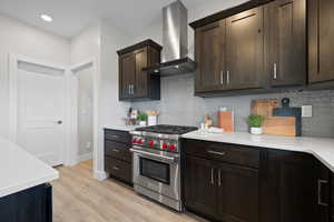 Designer Wolf range, light quartz countertops, tile backsplash, and dark wood cabinetry.