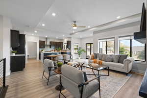 Open concept space featuring living room, dining room, and kitchen, LVP flooring, a tray ceiling, and recessed lighting.