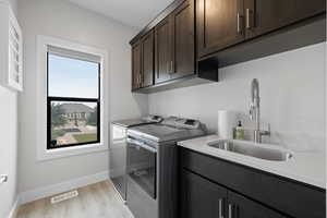 Laundry room featuring washing & dryer, dark wood cabinets, LVP flooring, and wash sink.