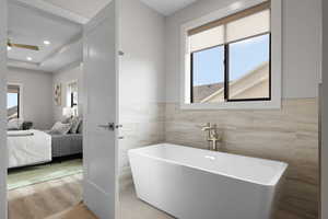 Primary bathroom featuring freestanding soaker tub with tile surround