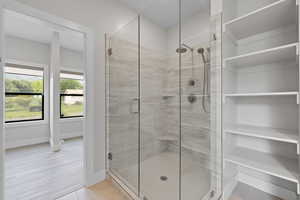 Primary bathroom featuring frameless glass shower, built-in linen storage, and walk-in closet