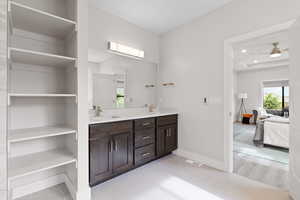 Ensuite bathroom featuring double vanity with dark wood cabinetry and light quartz counters, recessed lighting, and tile floors.