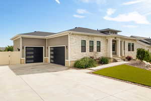 Modern prairie-style home with an attached garage, fenced yard, stone and Hardie side exterior, and heated driveway