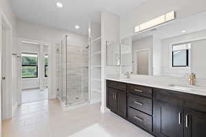Primary bathroom with double vanity, a euro-glass shower, tile floors, recessed lighting and walk-in closet.