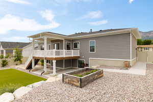 Back of property with stairway and covered deck, terraced landscaping, and open Flagstone patio
