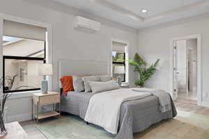 Primary bedroom featuring light LVP flooring, tray ceiling with recessed lighting, and a mini split for added comfort.