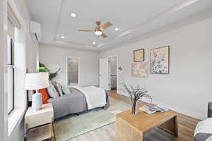 Primary bedroom featuring light LVP flooring, tray ceiling with recessed lighting, and a mini split for added comfort.