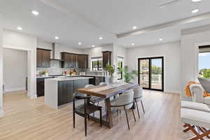 Open concept space featuring a dining room and kitchen, LVP flooring, a tray ceiling, recessed lighting, dark wood cabinets, quartz counters, and luxury appliances.