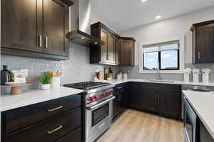 Kitchen featuring designer Wolf range, light quartz countertops, tile backsplash, Bosch dishwasher, dark wood cabinetry and LVP flooring.