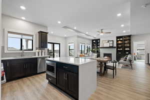 Open concept space featuring designer kitchen, spacious dining area, living room with gas fireplace and built-in cabinetry, LVP flooring, and recessed lighting.