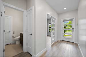 Entryway featuring modern-style front door, office entrance, LVP flooring, and a hallway half bathroom