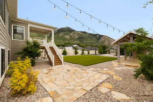 View of backyard including a covered Trex deck, Flagstone patio, Timber Pergola, professional landscaping and decorative lighting.