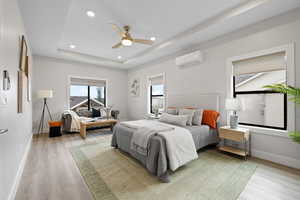 Primary bedroom featuring light LVP flooring, tray ceiling with recessed lighting, and a mini split for added comfort.