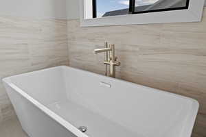 Primary bathroom featuring freestanding soaker tub with tile surround