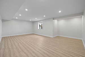 Basement living room featuring LVP flooring, recessed lighting, and daylight windows