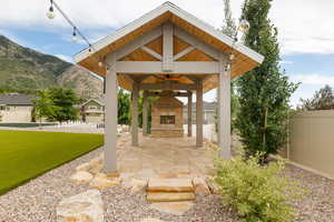 View of  covered patio featuring an outdoor stone fireplace, outdoor lighting, and a mountain view