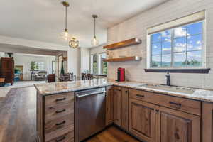 Kitchen featuring dishwasher, a peninsula, light stone countertops, backsplash, and dark wood finished floors