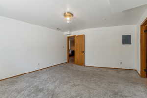 Spare room with electric panel, carpet flooring, and baseboards