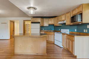 Kitchen featuring white appliances, under cabinet range hood, a sink, and light wood-style flooring