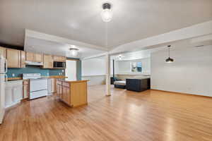 Kitchen with white appliances, light brown cabinetry, and light wood finished floors