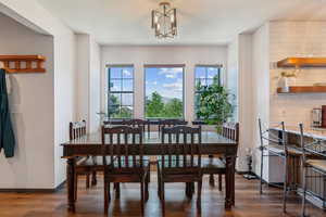 Dining room featuring dark wood-style floors, a chandelier, and baseboards