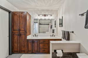 Bathroom with double vanity, tiled shower, and toilet