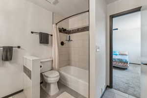 Full bathroom with toilet, shower / bath combination with curtain, baseboards, and tile patterned flooring