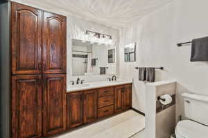 Bathroom with toilet, double vanity, and curtained shower