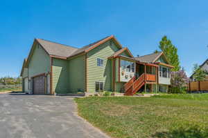 View of front of house with driveway, an attached garage, a front yard, roof with shingles, and stairway