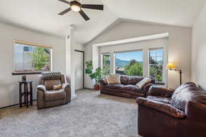 Carpeted living area featuring plenty of natural light, a ceiling fan, and vaulted ceiling