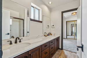 Bathroom featuring double vanity, wood finished floors, and an enclosed shower